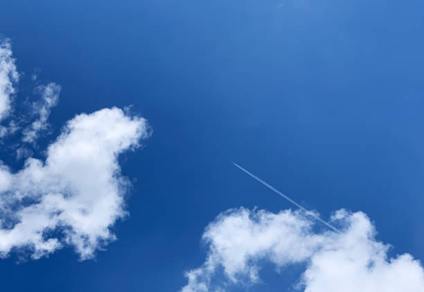 istock Airplane vapor trail above cumulus clouds 1250716277