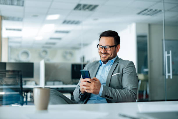 istock Cheerful businessman using smart phone in the office, portrait. 1250720962