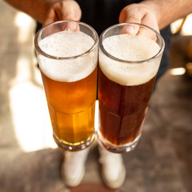 istock Man holding white and black beer side by side close up 1250721058