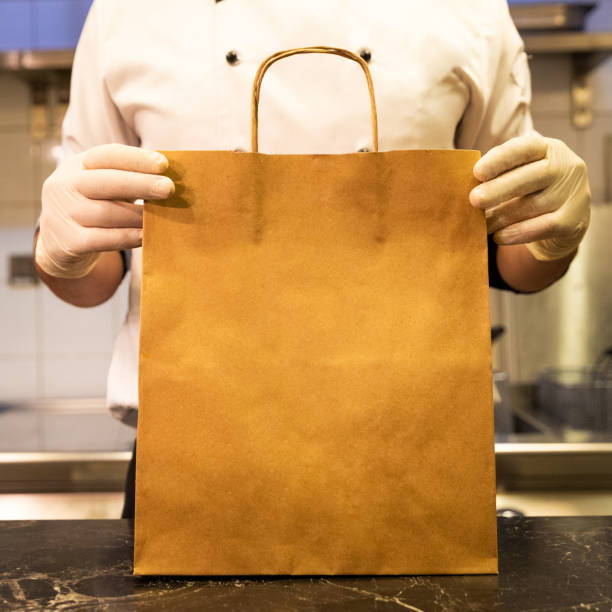 chef hält lebensmittel-liefertasche - lunch take out food bag paper bag stock-fotos und bilder