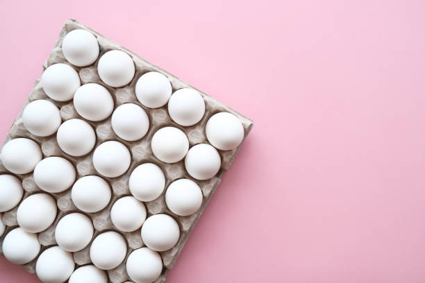 istock Egg carton box with thirty chicken eggs on pink background. 1250721567
