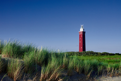 Ouddorp lighthouse, red tower with white top, blue sky and green meadow. Netherlands