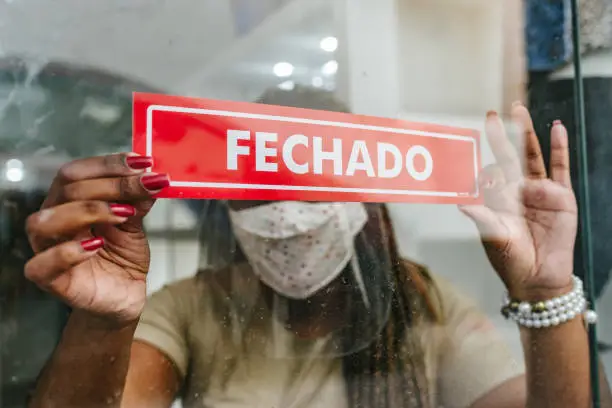 Photo of Bankruptcy: Woman hanging CLOSED notice in store