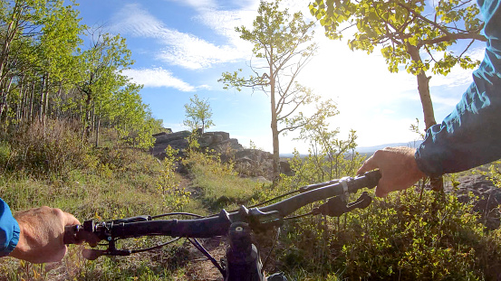 POV from behind his handlebars, sun shines over distant Canadian Rocky Mountains