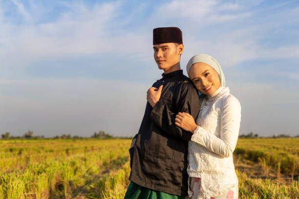 Beautiful Malay Couple posing for portrait Young and beautiful heterosexual Muslim couple taking photo in front of a Paddy field in Sekinchan, Malaysia happy malay couple stock pictures, royalty-free photos & images