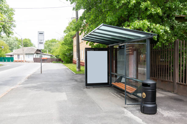 public transport stop in the city with an empty place for an advertising poster banner. near trees and houses. horizontal orientation - bus stop imagens e fotografias de stock