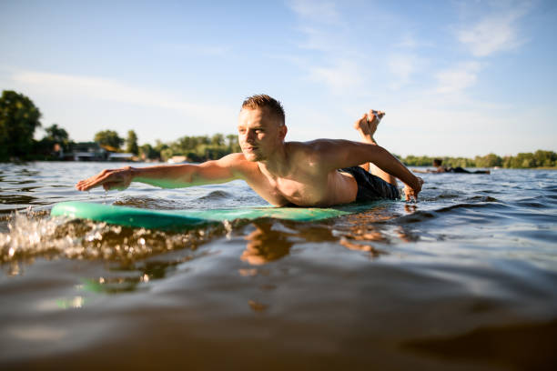 istock man lies on a surfboard, rows his hands and floats on the river. 1250724617