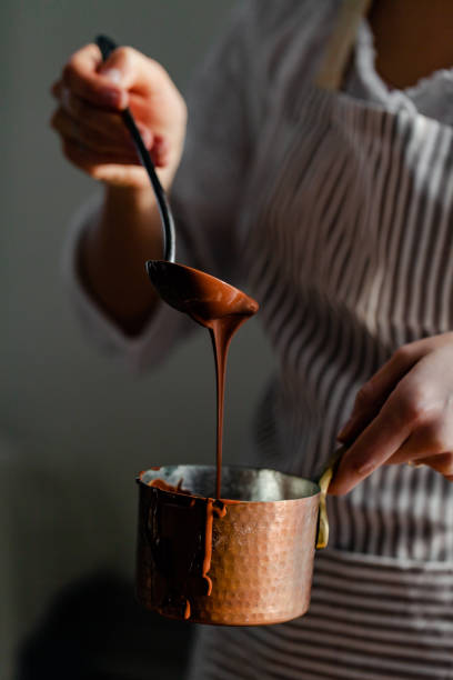 hermosa joven en delantal beige está preparando delicioso chocolate caliente orgánico en el viejo cordón vintage. luz diurna suave, fotografía de estilo de vida, proceso de creación de bebidas sabrosas. de cerca - chocolate pot de creme fotografías e imágenes de stock