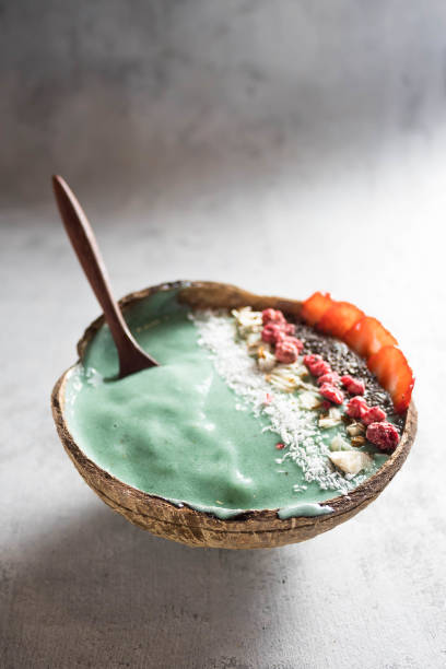 coconut bowl with banana ice cream with spirulina and garnished with berries and seeds