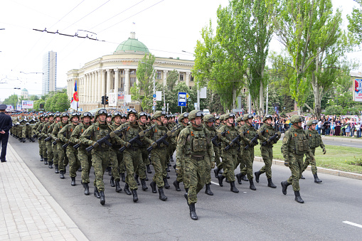 DONETSK, Donetsk People Republic, Ukraine, May 9, 2018: Military men in full uniform with arms march along the main street of the city during the parade in honor of Victory Day in World War II.
