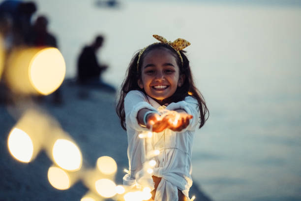 fille jouant avec des lumières de fée à la plage - beach ideas photos et images de collection