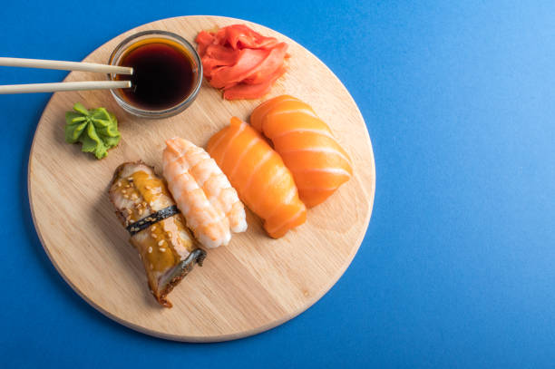 간장과 젓가락이 있는 나무 접시에 맛있는 식욕을 돋우는 니기리 초밥 세트. 파란색 배경 - chopsticks soybean japanese cuisine blue 뉴스 사진 이미지
