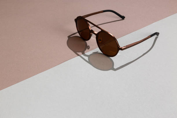 istock Round metal classy sunglasses lit with hard light with shadow on abstract diagonal brown background with empty space 1250777539