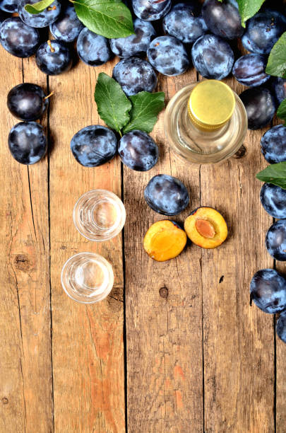 shots of slivovice, typical eastern europe alcohol plum brandy and bottle at background. view from above. vertical photo. - plum fruit organic food and drink imagens e fotografias de stock