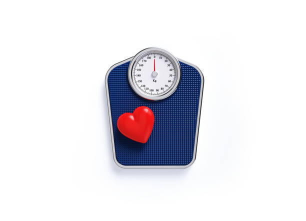 istock Red Heart Sitting over Blue Bathroom Scale on White Background 1250779974
