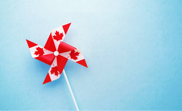 Paper pinwheel pair textured with Canadian flag on blue background. Horizontal composition with copy space. Front view. Canada Day concept.