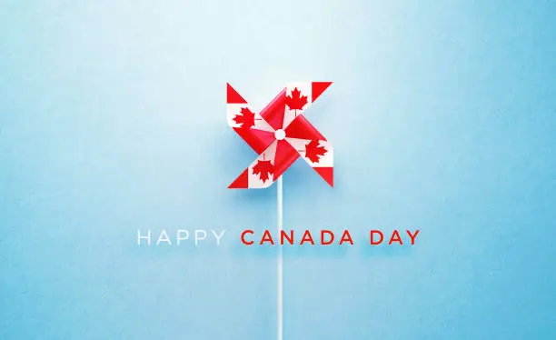 Happy Canada Day message and paper pinwheel textured with Canadian flag on blue background. Horizontal composition with copy space. Front view. Canada Day concept.