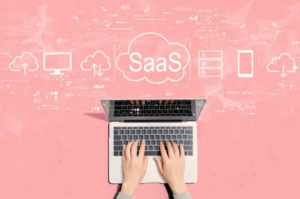 Photo of SaaS - software as a service concept with person using laptop