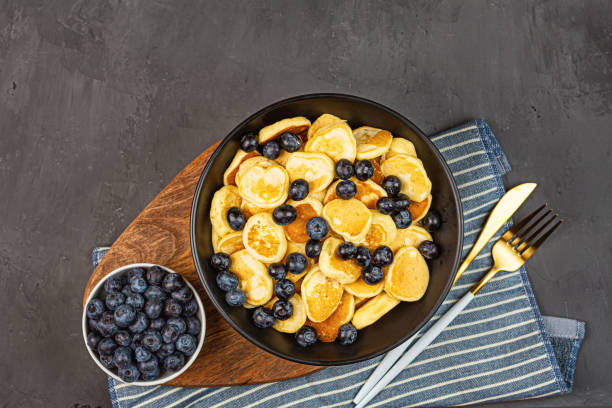 istock Trendy home breakfast with tiny pancakes and blueberry on gray concrete background. Flat lay, top view, overhead, mockup, template, copy space. View from above 1250815248