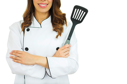 Female chef holding a spatula smiling with arms crossed