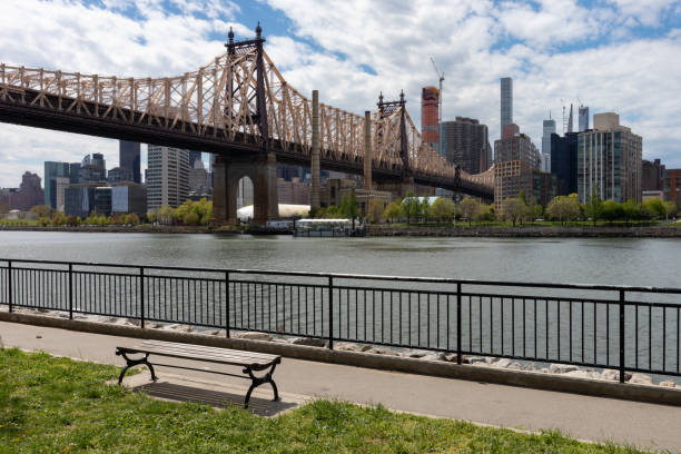 istock Queensbridge Park along the East River with the Queensboro Bridge and an Empty Bench during Spring in Long Island City Queens New York 1250831161