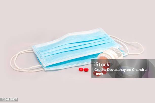 Personal Protective Face Masks That Are Currently In In Use Around The World To Prevent The Spread Of Covid19 Together With Vitamin D Capsules And B Complex Placed On A White Cloth Studio Shot Stock Photo - Download Image Now