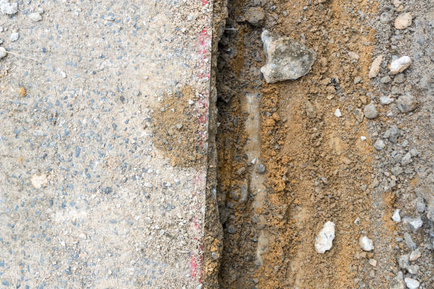 istock Digging road before install Pipe Water  . Excavation water drainage at construction site. Digging roads to lay pipes 8 inches. The road repair and caution with blocked barrier over concrete digging. 1250844120