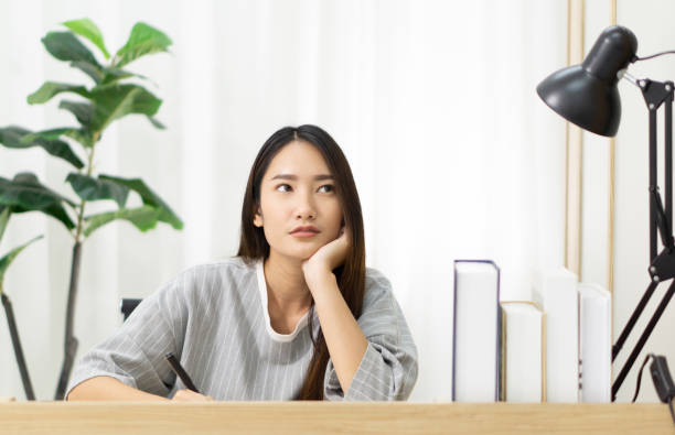 istock Studious young woman studying at home with a textbook from university 1250848530