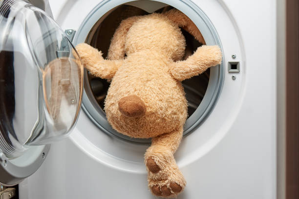 istock Stuffed toy rabbit with his back in the washing machine. 1250849835