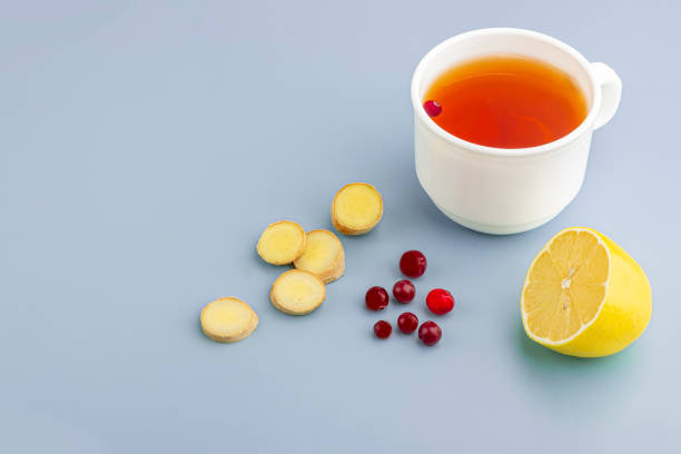 Cup of tea, ginger, lemon and cranberry as folk remedies on blue background  with copy space for text. The concept of seasonal diseases and treatment of colds, flu, heat. Prevention of virus