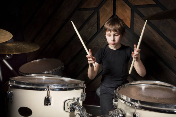 istock A boy is playing with a drumstick. The child behind the drum kit. 1250908475