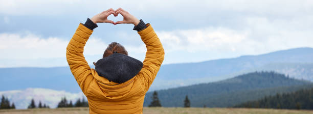 mujer disfrutando en la naturaleza con paisaje montañoso en el fondo. - heart shape loneliness women praying fotografías e imágenes de stock