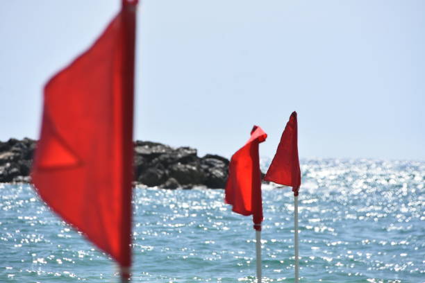 Red and yellow flag against clear sky, sun