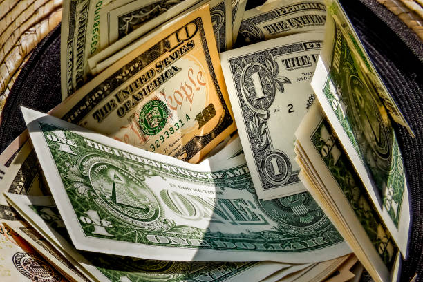 straw hat with a stack of dollar bills inside, donated to a successful beggar