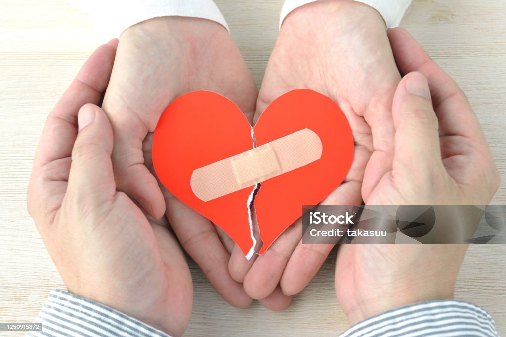Couple's hands having broken heart with adhesive plaster Reconciliation Stock Photo
