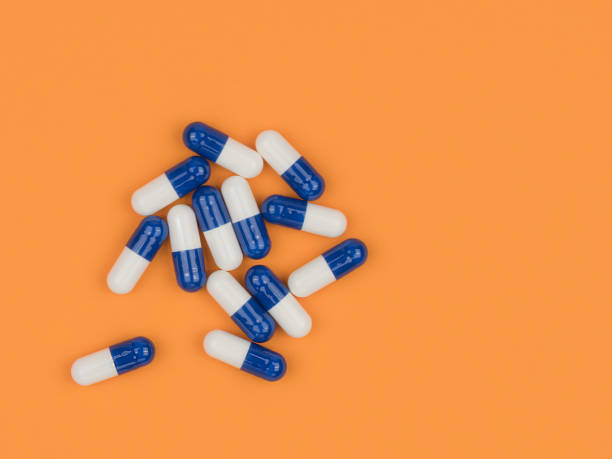 istock Blue pills, capsules on an orange background. 1250917634