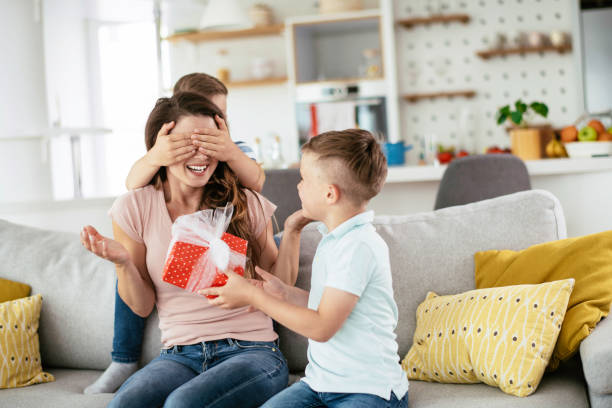 dwaj młodzi synowie dają matce prezent. - gift mothers day birthday giving zdjęcia i obrazy z banku zdjęć