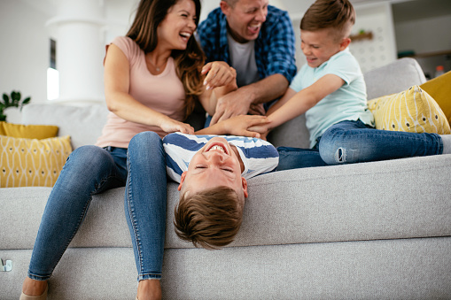 Young family enjoying at home Happy parents tickling son and having fun.