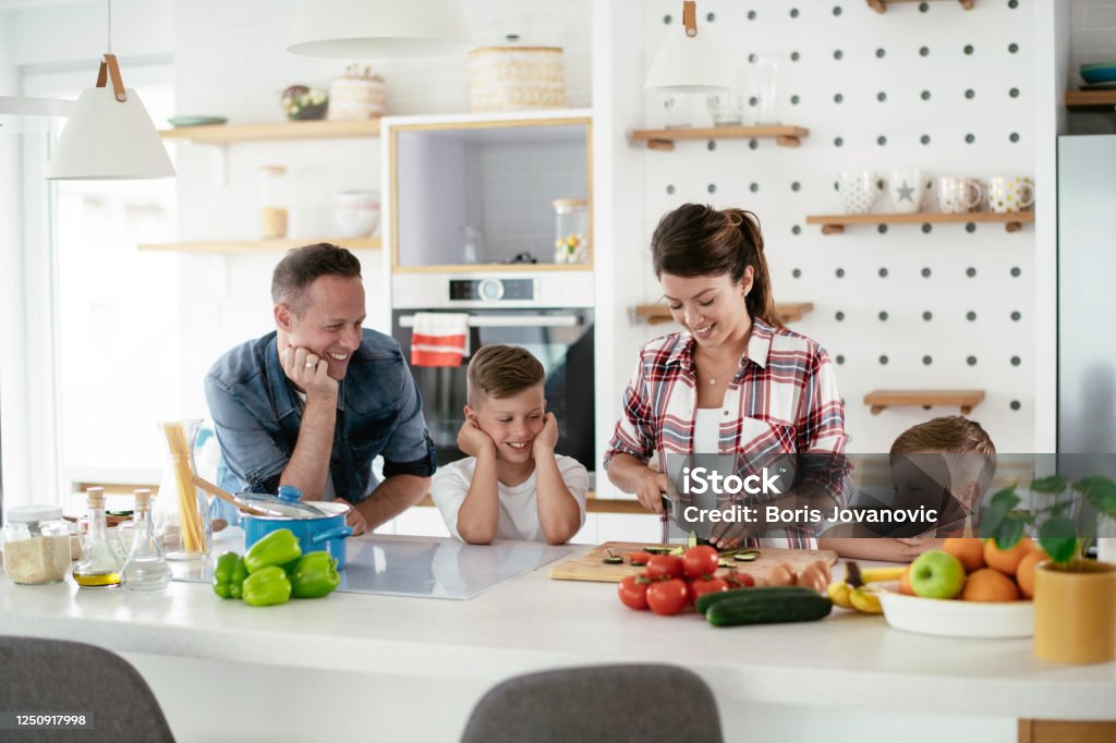 Young happy family making sandwich at home Young happy family making sandwich at home. Mom and dad preparing breakfast with sons. Happiness Stock Photo