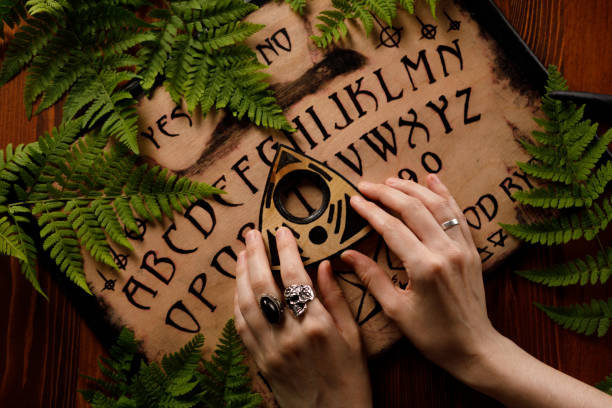 Mystic ritual with Ouija and candles. Devil's board concept, black magic or fortune telling rite with occult and esoteric symbols. stock photo