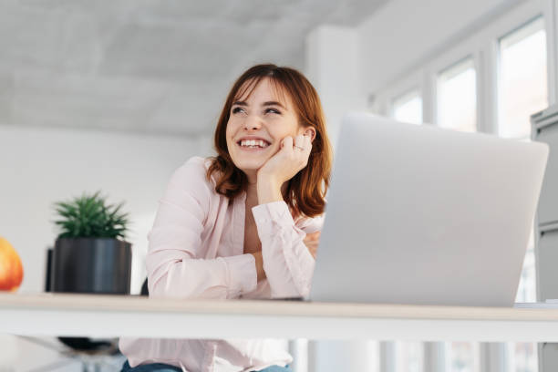 istock Happy young office employee seated at her desk 1250919638