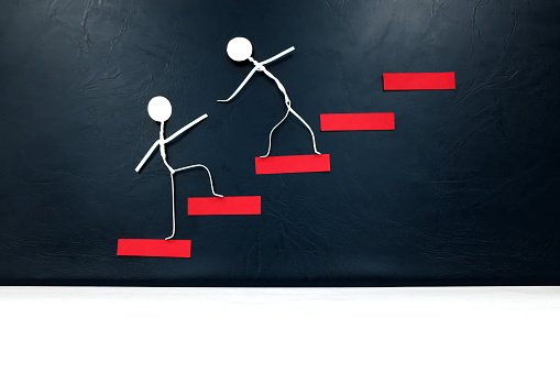 Helping hand, support and teamwork concept. Two human stick figures climbing a red ladder.