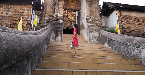 The red dress in a back-facing position with the door to the temple.
