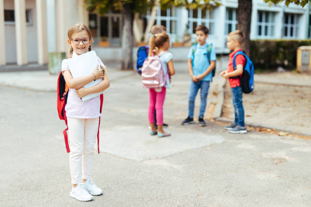 istock School girl standing outside school with rucksack and textbook 1250926514