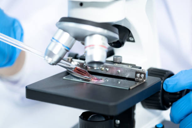 istock Young man using a microscope to see coronavirus (Covid-19) in a laboratory. He drops the dilution of blood samples in the glass. Researchers find a vaccine to prevent the virus. 1250926854