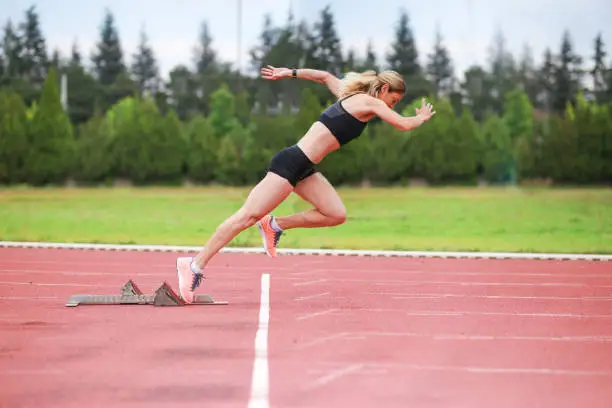 Track athlete exploding out of the starting blocks in stadium