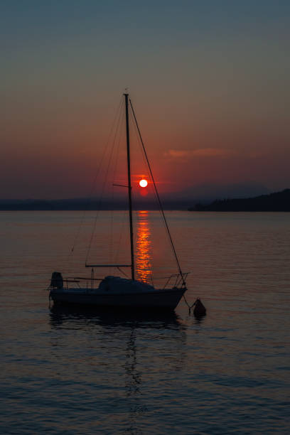 カラフルな夕日を持つ穏やかな湖ガルダの帆船 - lake garda sunset blue nautical vessel ストックフォトと画像