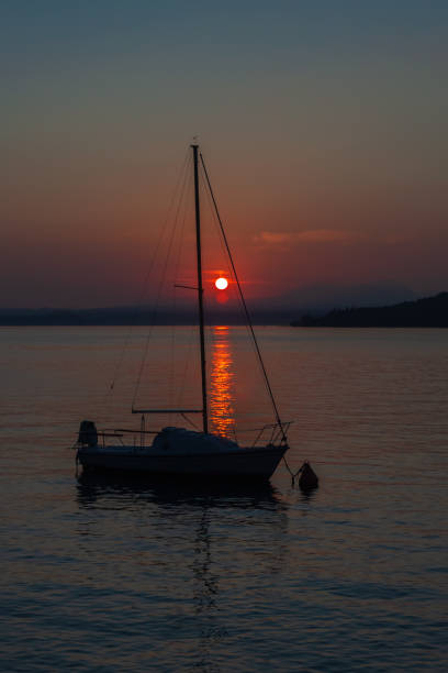 парусник на спокойном озере гарда с красочным закатом - lake garda sunset blue nautical vessel стоковые фото и изображения