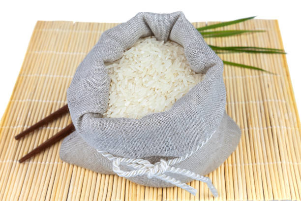 Macro view of sack of white rice with greens on the mat isolated on white background