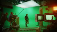 istock In the Big Film Studio Professional Crew Shooting Blockbuster Movie. Director Commands Cameraman to Start shooting Green Screen CGI Scene with Actor Wearing Motion Capture Suit and Head Rig 1250933117